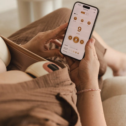 Een mama op haar gsm terwijl ze kolft met de cura handsfree borstkolf