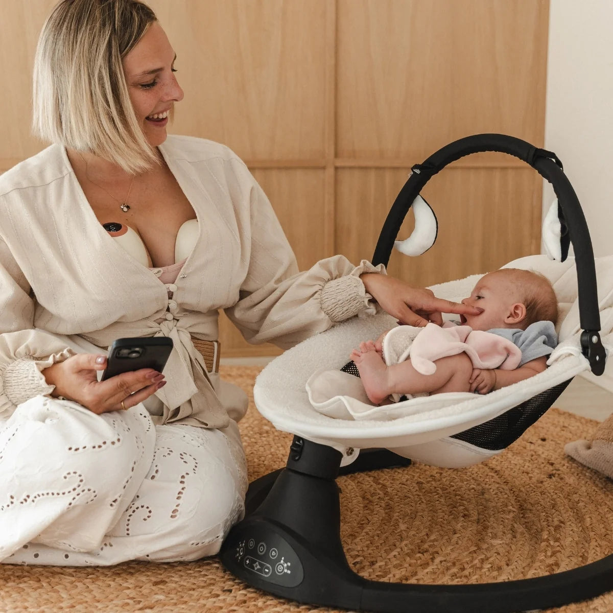 Een mama en haar baby in een stoel terwijl ze kolft met de Cura handsfree borstkolf